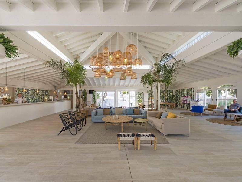 Offener, moderner Wohnbereich mit weißen Holzbalken, Pflanzen, Sitzgruppen und natürlichem Licht.