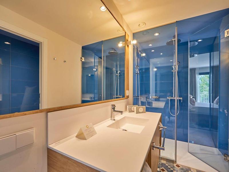 Moderner Badbereich mit Glasdusche, weißem Waschbecken und großen Spiegeln an der Wand.