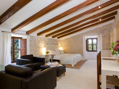 Lichte hotelkamer met houten balken, stenen muren, tweepersoonsbed en lederen zithoek.