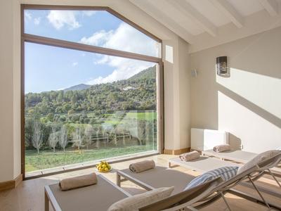 Jasne spa z leżakami i dużymi oknami z widokiem na zielone wzgórza.