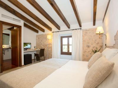 Przytulny pokój hotelowy z drewnianymi belkami, łóżkiem podwójnym i miejscem do pracy z telewizorem.