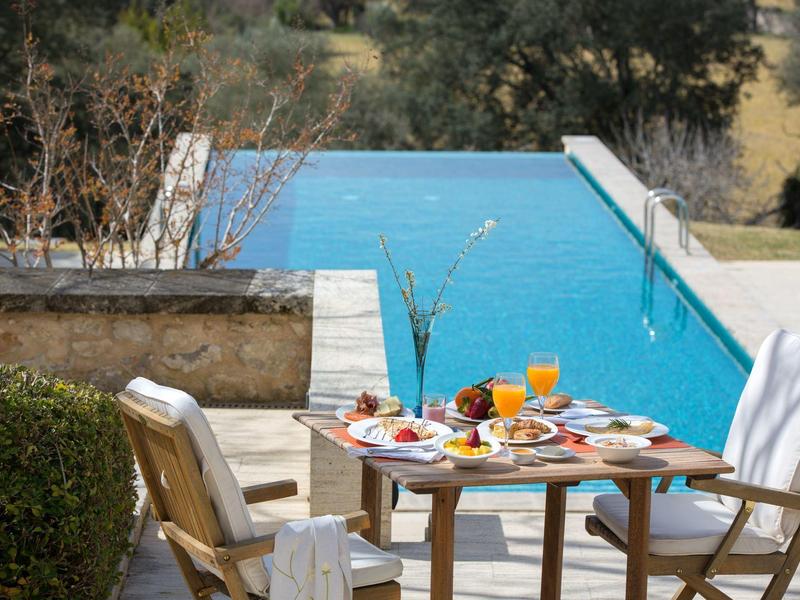 Stół na śniadanie z sokiem pomarańczowym i jedzeniem obok basenu na tarasie.