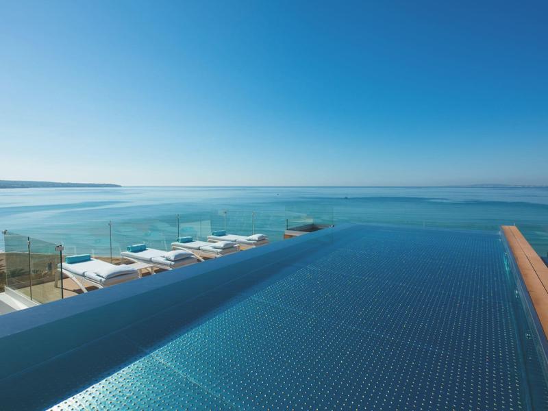 Unendlicher blauer Pool mit Meerblick und blauem Himmel im Hintergrund.