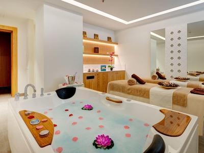 Spa moderno con vasca idromassaggio e letti per il relax con luce soffusa.