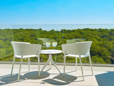Due sedie bianche e un tavolo con vino su una terrazza con vista sulla foresta.
