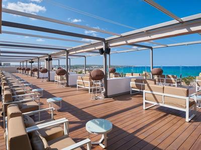 Area terrazza aperta con posti a sedere e vista sul mare sotto un cielo limpido.