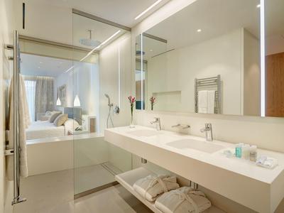 Helles Badezimmer mit großer Glasdusche, Doppelwaschbecken und großem Spiegel.