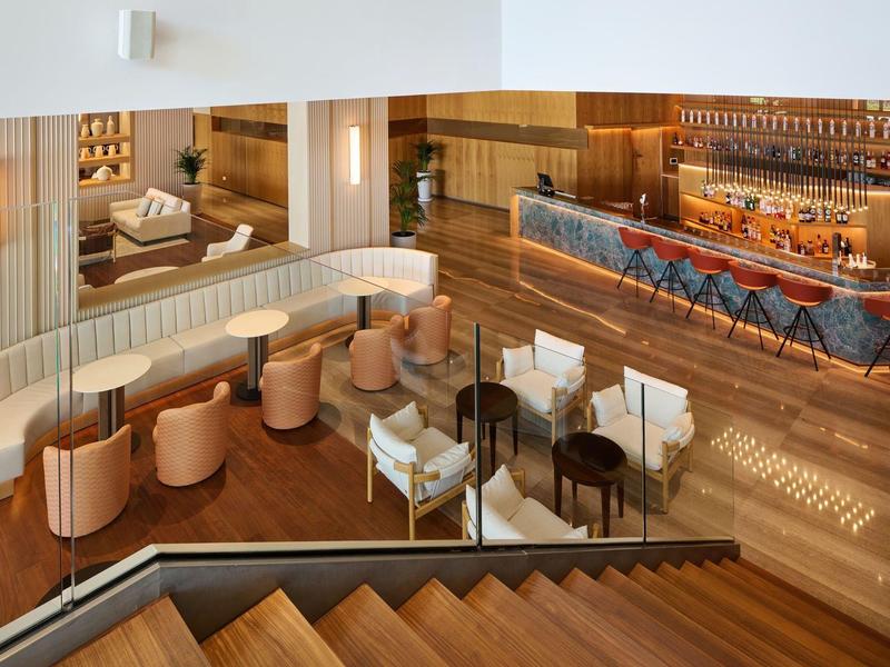 Bar elegante in hotel con aree salotto e pavimento in legno accanto alla scala.