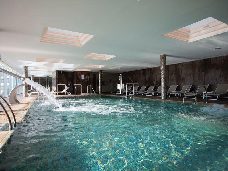 Piscina interna con getti massaggianti e lettini in un hotel benessere.