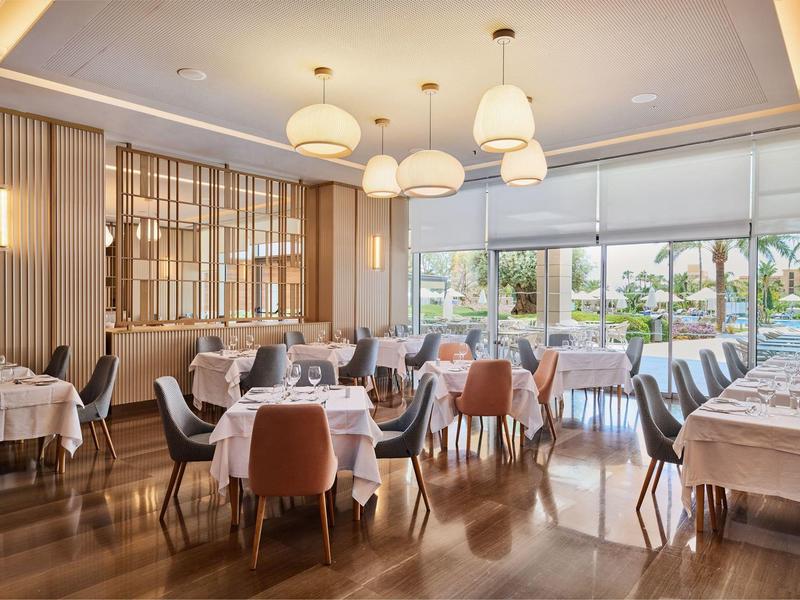 Ristorante luminoso e moderno con grandi finestre e tavoli apparecchiati.