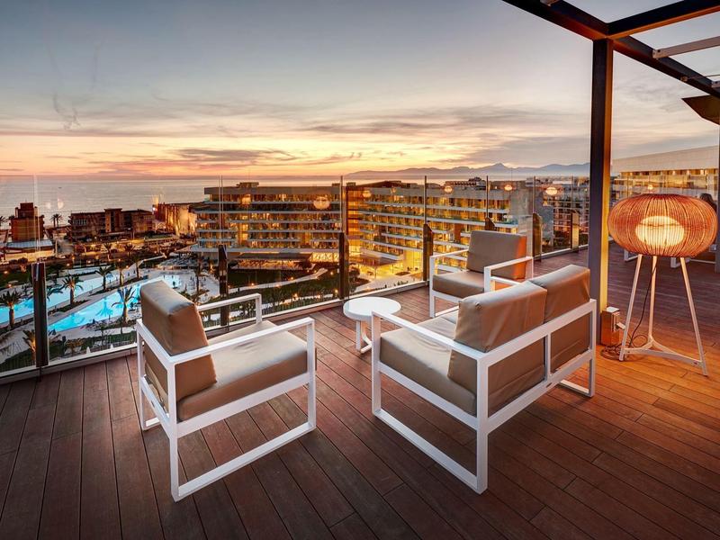 Terrazza con mobili lounge moderni e vista sul mare al tramonto.