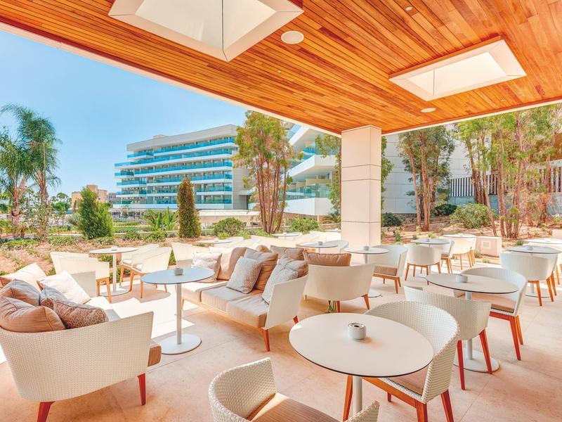 Terrazza di hotel moderna con sedute bianche e arredi in legno chiaro.