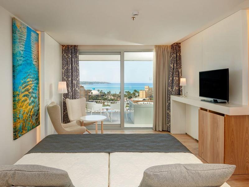 Camera d'hotel moderna con vista mare, balcone e arredi minimalisti.