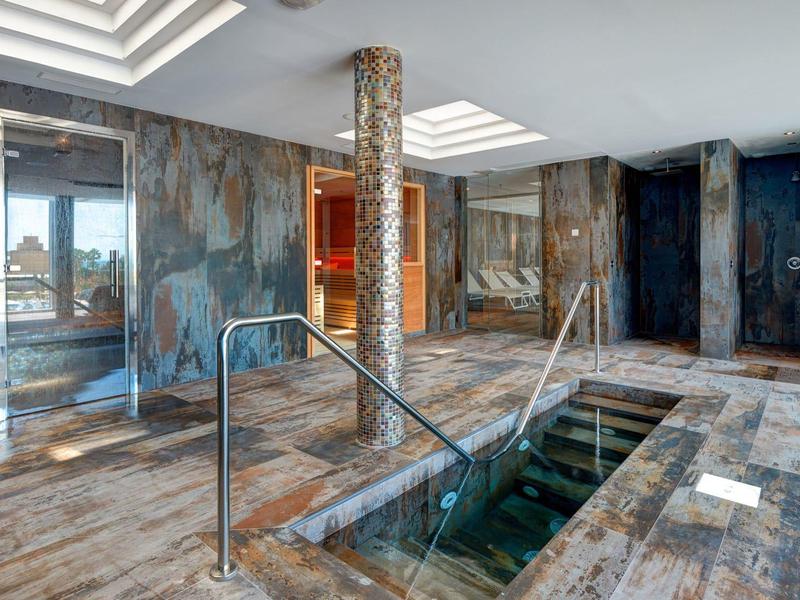 Piscina interna con vasca idromassaggio, pareti affrescate e soffitti luminosi.