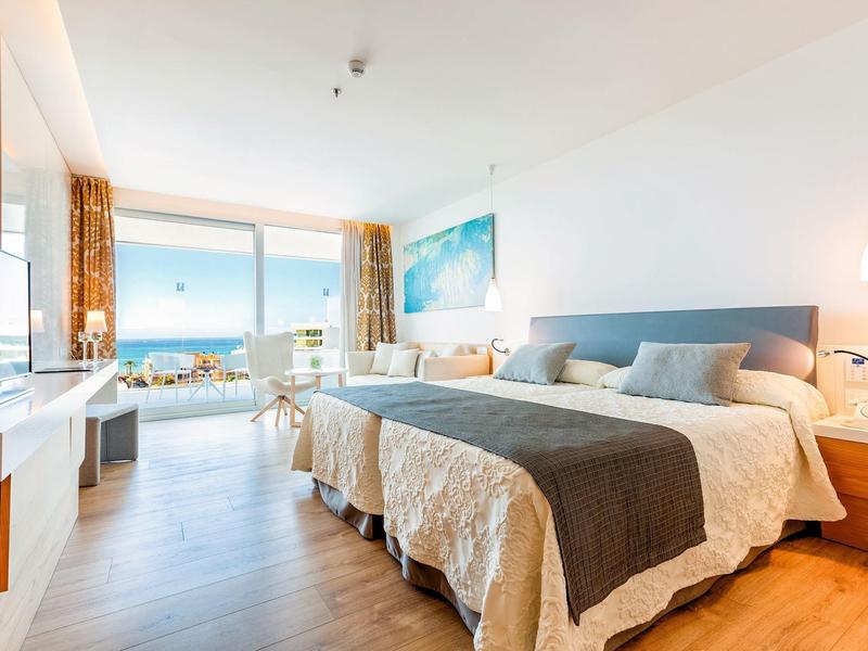 Camera d'albergo luminosa con due letti, vista sul mare e arredamento moderno.