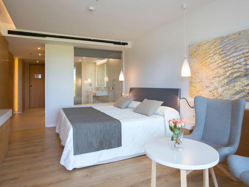 Camera d'hotel moderna con letto matrimoniale, area salotto e arredamento elegante.