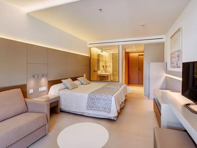 Camera d'hotel accogliente con letto matrimoniale, divano e bagno moderno.