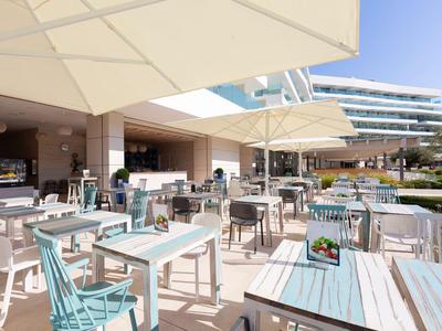 Splendida terrazza esterna dell'hotel con tavoli, sedie e grandi ombrelloni.