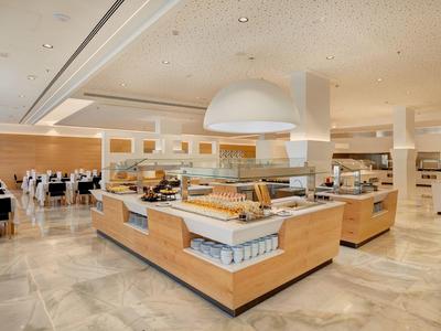 Großer, moderner Buffetbereich mit hellem Holz, Marmorboden und verschiedenen Essensstationen.
