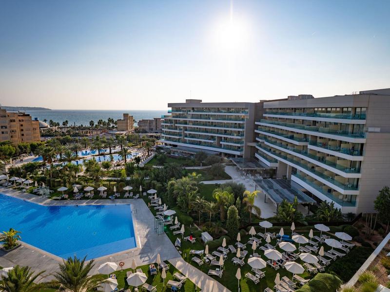 Hotel moderno con piscina all'aperto e lettini sotto un cielo soleggiato.