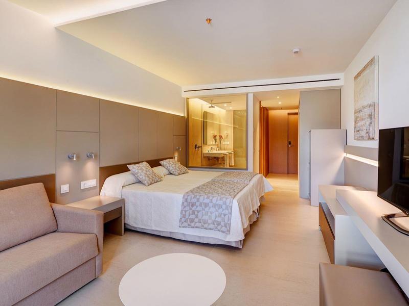 Camera d'hotel accogliente con letto matrimoniale, divano e bagno moderno.