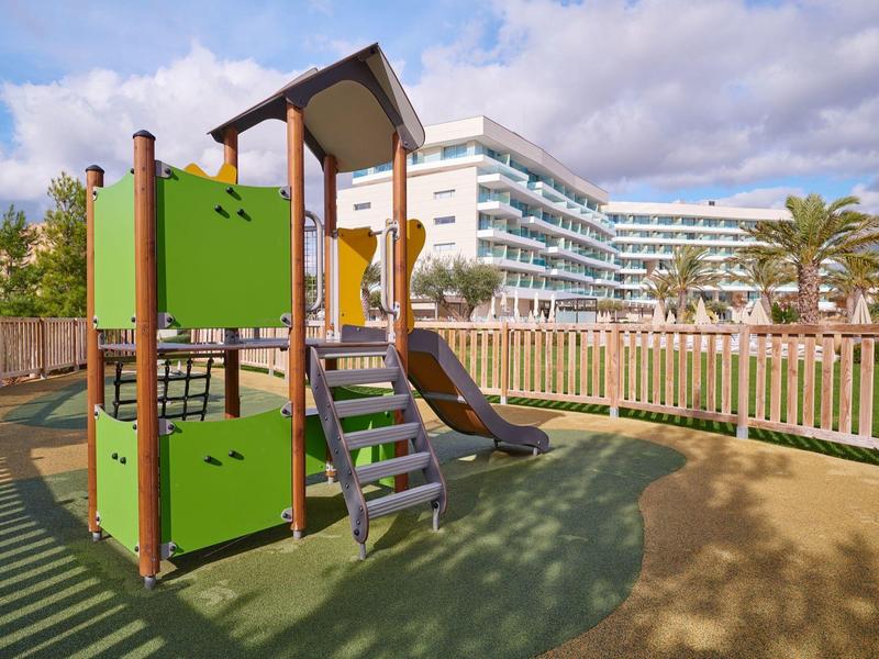 Parco giochi con scivolo davanti a un edificio moderno dell'hotel.
