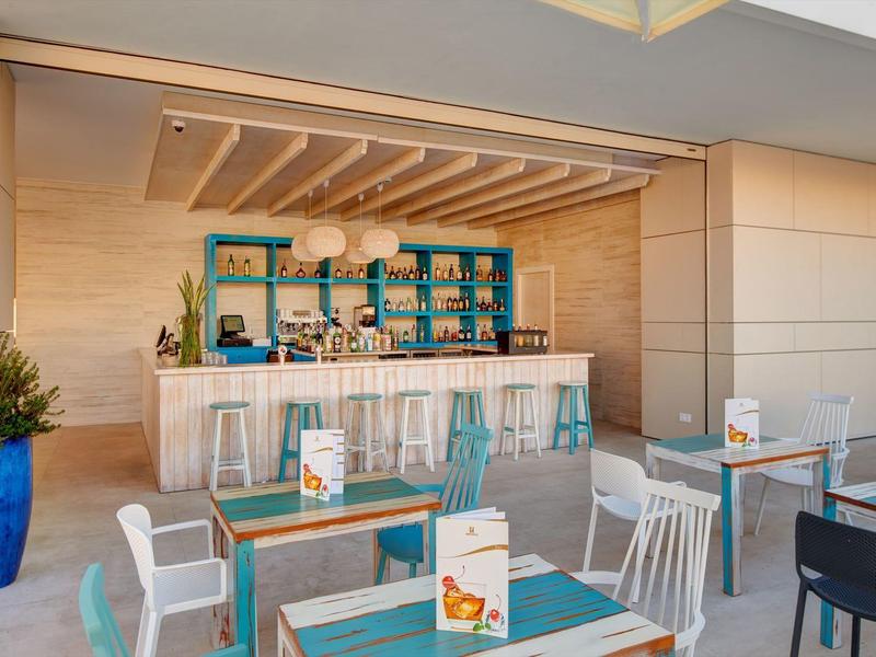 Caffè moderno con area bar, accenti blu, pannelli in legno chiaro e posti a sedere interni.