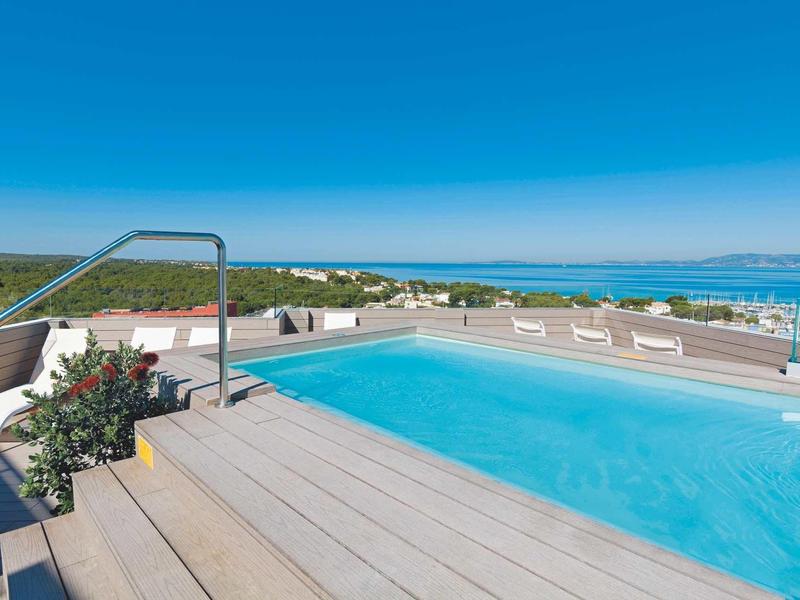 Rooftop pool with clear blue water and ocean view under a sunny sky.