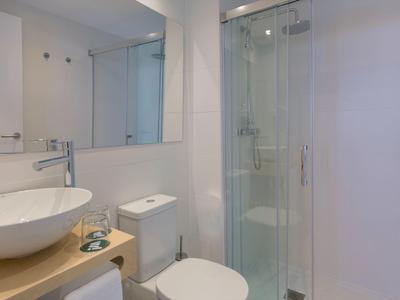 Mała nowoczesna łazienka z okrągłą umywalką, toaletą i kabiną prysznicową z drzwiami szklanymi.