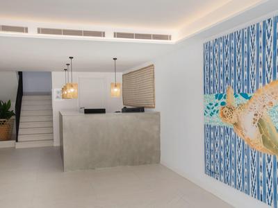 Nowoczesna recepcja hotelu z minimalistycznym biurkiem i dużą mozaiką ścienną żółwia morskiego.