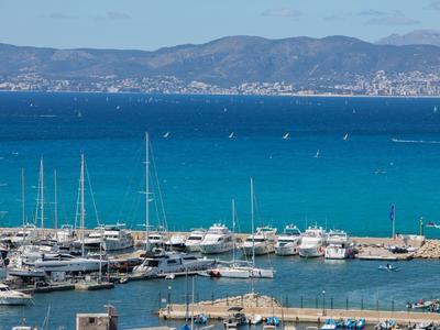 Port z żaglówkami i turkusowym morzem na tle górzystego wybrzeża pod niebieskim niebem