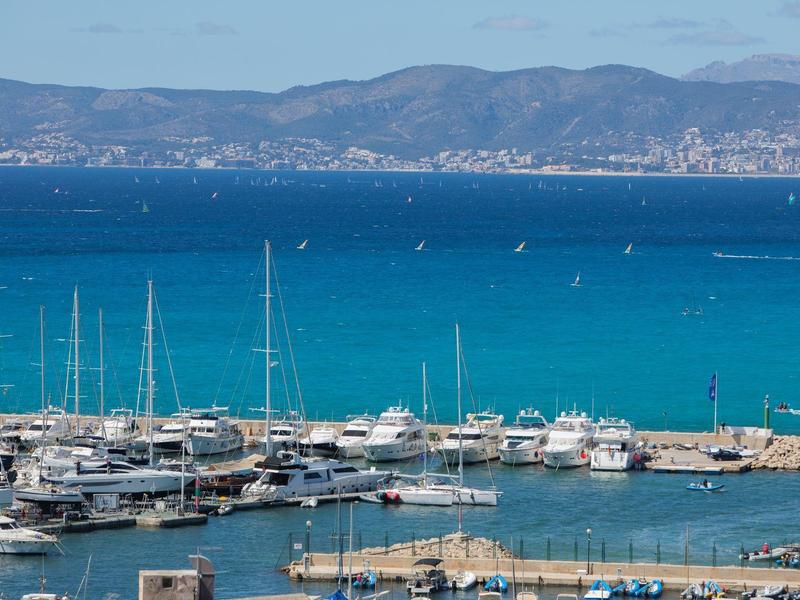 Port z żaglówkami i turkusowym morzem na tle górzystego wybrzeża pod niebieskim niebem