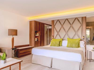 Chambre d'hôtel moderne avec lit double, accents en bois et coin salon confortable.