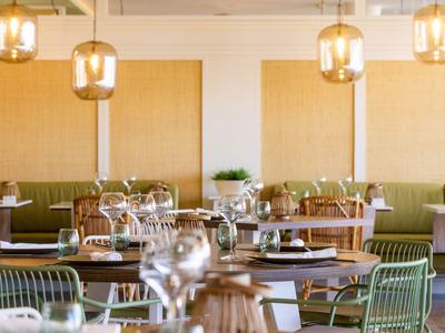 Restaurant moderne avec tables dressées et chaises vertes dans une ambiance lumineuse