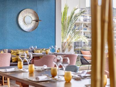 Salle à manger moderne avec des chaises roses et des bougies jaunes sur les tables, ambiance lumineuse.