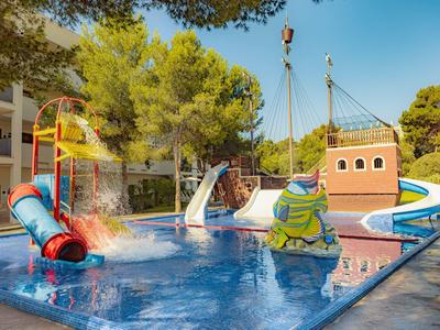 Piscine pour enfants avec toboggans colorés et aire de jeux aquatique entourée d'arbres au soleil