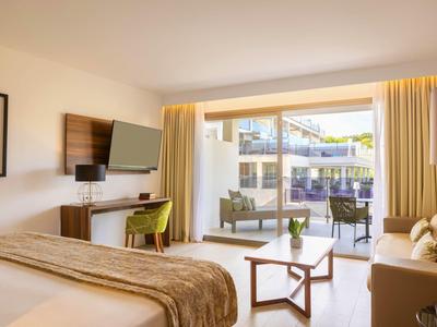 Chambre d'hôtel moderne avec lit, bureau, télévision et balcon donnant sur l'extérieur.