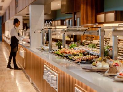 Buffet avec divers plats dans un restaurant d'hôtel moderne, serveur en arrière-plan.