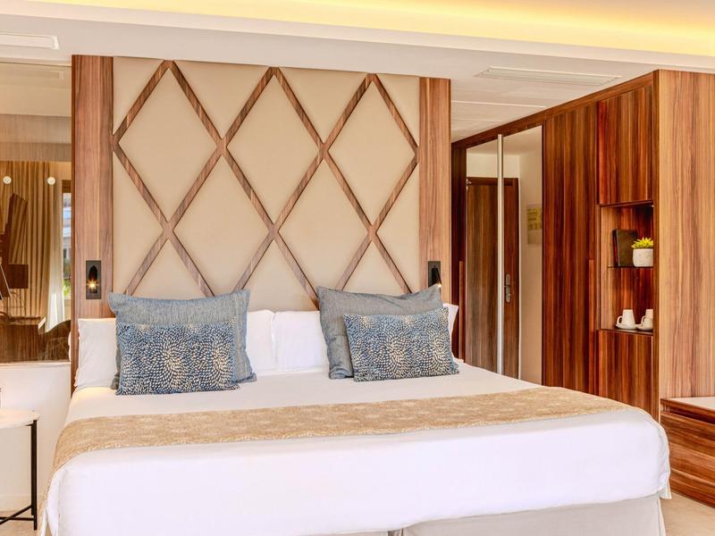 Chambre d'hôtel moderne avec grand lit et panneau en bois décoratif au mur.