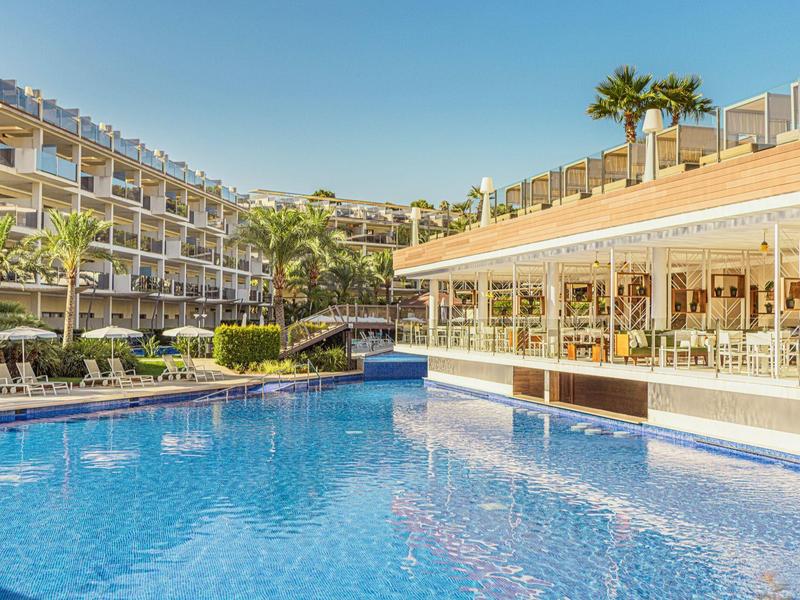 Grande piscine extérieure avec transats et bâtiments de l'hôtel par temps ensoleillé