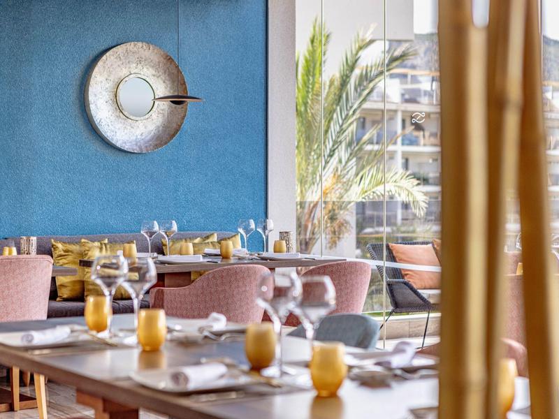 Salle à manger moderne avec des chaises roses et des bougies jaunes sur les tables, ambiance lumineuse.