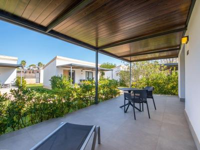 Terras met stoelen en tafel omgeven door groen, moderne buitenruimte van een huis.