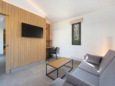 Modern ingerichte woonkamer met grijze bank, houten wand en kleine tafel.