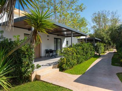 Moderne hotelbungalows met terrassen in een groene, zonnige tuin.