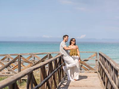 Koppel staat op houten pier met uitzicht op zee op een zonnige dag.