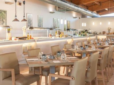 Moderne hotelrestaurant met gezellige beige stoelen en netjes gedekte houten tafels.