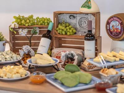 Tafel met verschillende kaassoorten, wijnflessen, druiven en sauzen voor een gastronomische proeverij.