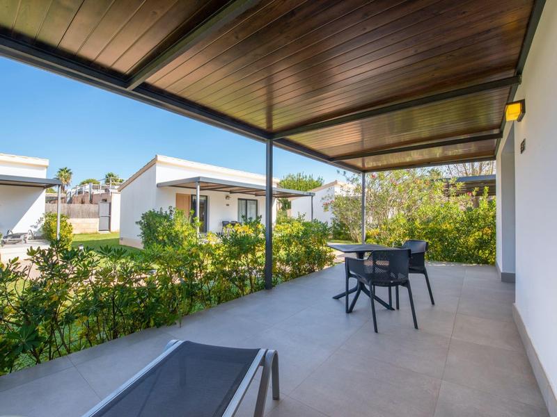 Terras met stoelen en tafel omgeven door groen, moderne buitenruimte van een huis.
