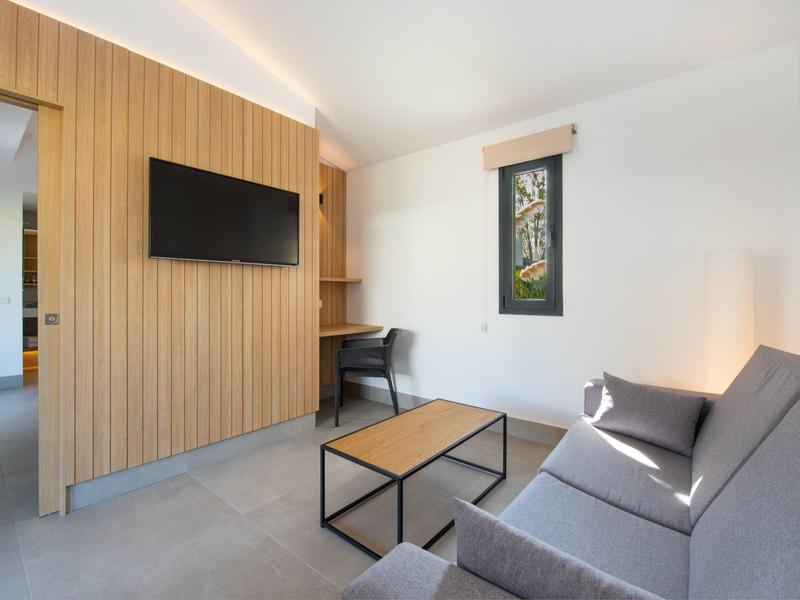 Modern ingerichte woonkamer met grijze bank, houten wand en kleine tafel.