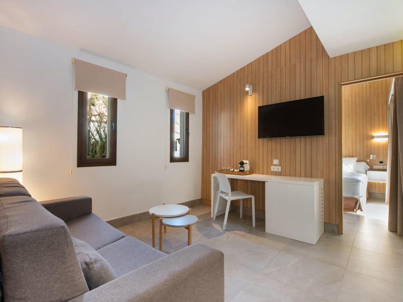 Modern ingerichte hotelkamer met sofa, bureau en wand-tv.